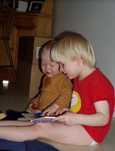 Harald läser för Artur medan mamma fyller en pafflåda Harald läser för Artur medan mamma fyller en pafflåda